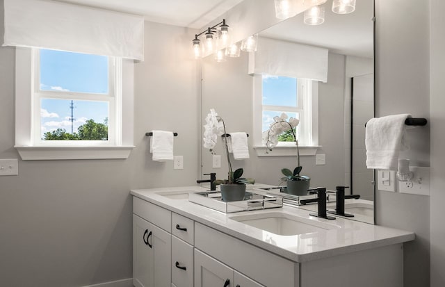 bathroom with double vanity, a sink, and baseboards