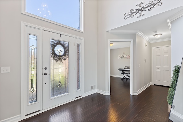 foyer featuring visible vents, crown molding, a towering ceiling, baseboards, and dark wood-type flooring