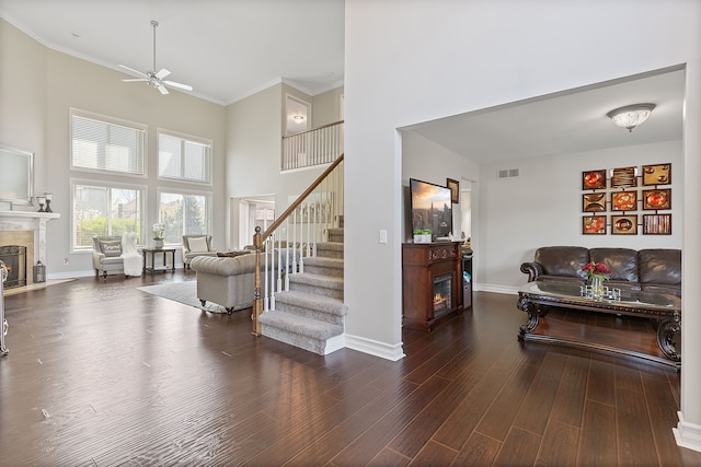 living area featuring a high end fireplace, baseboards, ceiling fan, and a towering ceiling