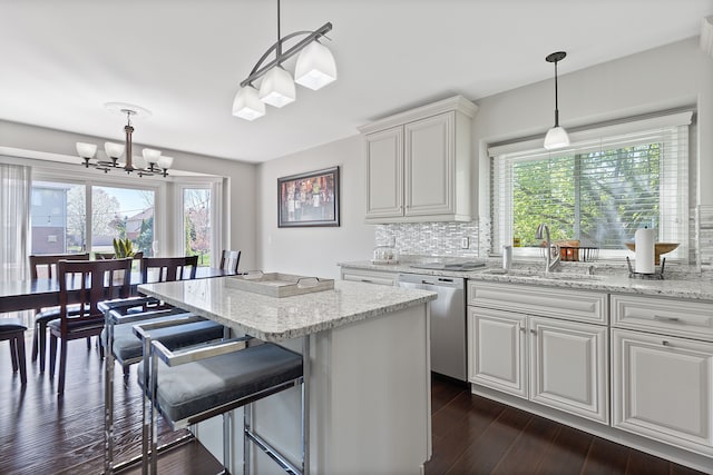 kitchen featuring stainless steel dishwasher, an inviting chandelier, white cabinets, tasteful backsplash, and a sink