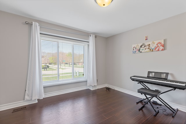 interior space with baseboards, dark wood finished floors, and visible vents