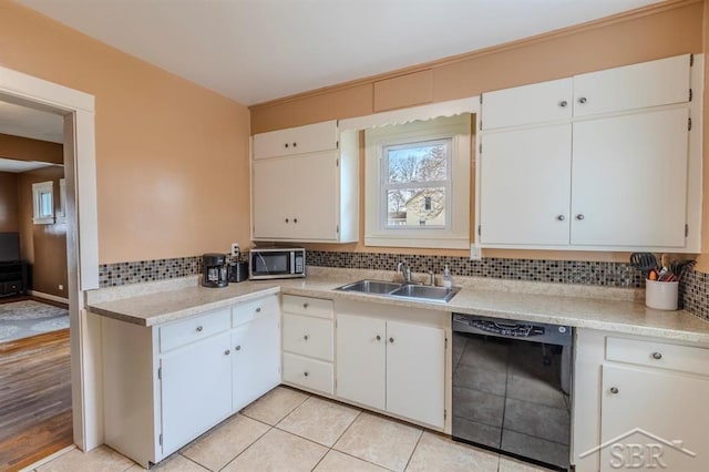 kitchen featuring decorative backsplash, dishwasher, a sink, light countertops, and stainless steel microwave