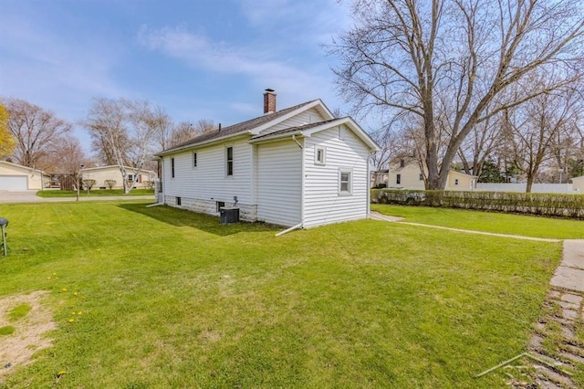 view of side of home featuring a yard, a chimney, and central air condition unit