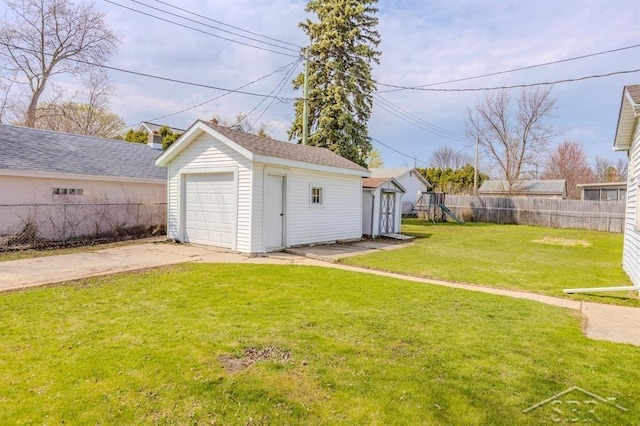 detached garage featuring fence and driveway