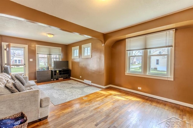 unfurnished living room featuring visible vents, baseboards, and wood-type flooring