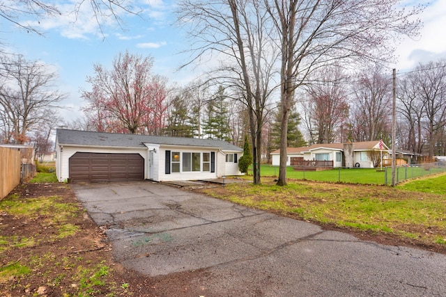 ranch-style house featuring a garage, fence, driveway, and a front yard
