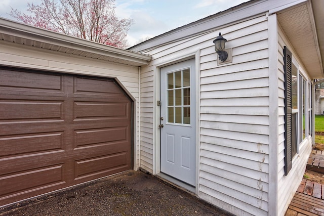 doorway to property with an attached garage and aphalt driveway