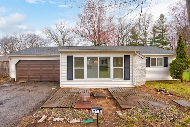 exterior space with a garage, a shingled roof, and aphalt driveway