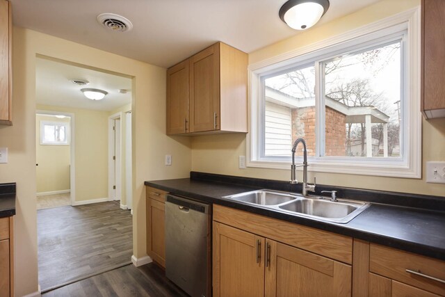 kitchen with dark wood-style flooring, dark countertops, a sink, stainless steel dishwasher, and visible vents