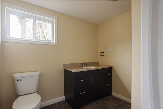 bathroom featuring baseboards, vanity, and toilet