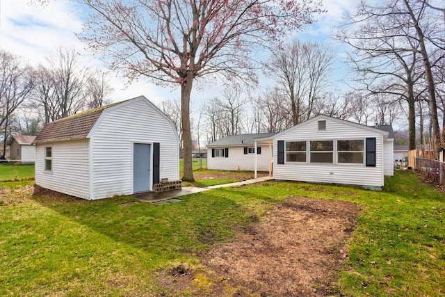 back of property with a lawn, fence, an outbuilding, and a gambrel roof