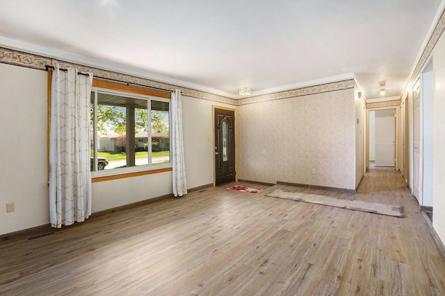 unfurnished room with crown molding, baseboards, visible vents, and light wood-style flooring