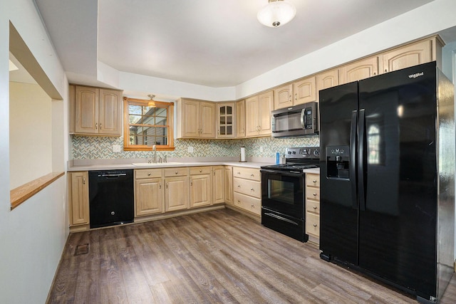 kitchen featuring dark wood-type flooring, a sink, black appliances, and light brown cabinets