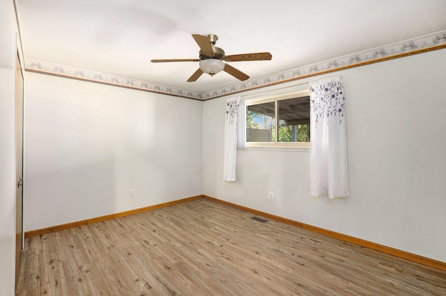 empty room with baseboards, ceiling fan, wood finished floors, and visible vents