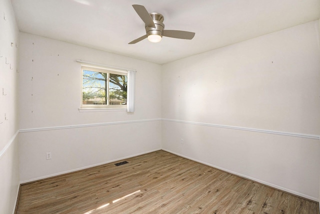 spare room with baseboards, ceiling fan, wood finished floors, and visible vents