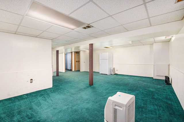 finished below grade area featuring carpet floors, freestanding refrigerator, a paneled ceiling, and visible vents