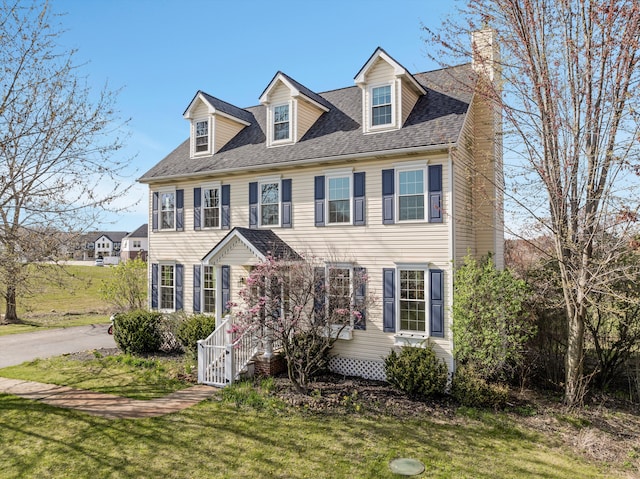 colonial home featuring a front lawn and a chimney