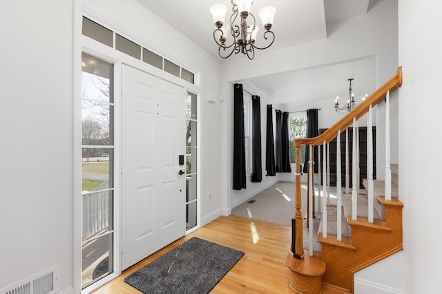 entrance foyer featuring visible vents, stairs, wood finished floors, baseboards, and a notable chandelier
