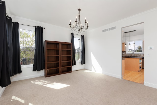 unfurnished room with visible vents, crown molding, baseboards, an inviting chandelier, and carpet