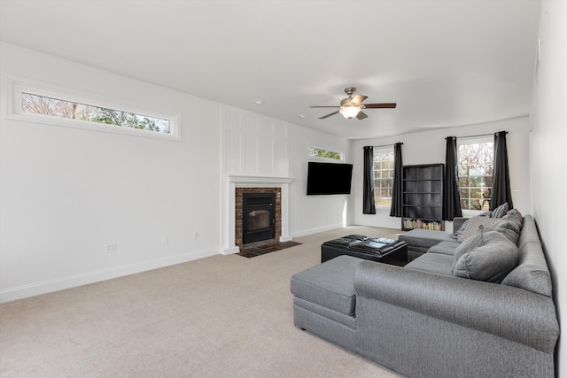 living area featuring a fireplace with flush hearth, light carpet, a ceiling fan, and a wealth of natural light