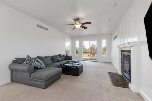 living room featuring a ceiling fan, visible vents, a fireplace, carpet floors, and baseboards