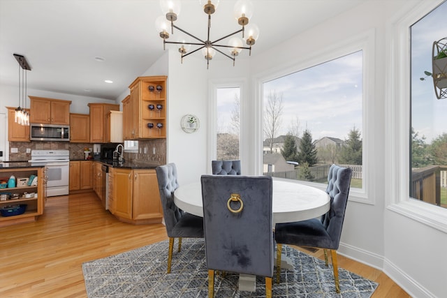 dining area featuring baseboards, light wood finished floors, a chandelier, and a healthy amount of sunlight