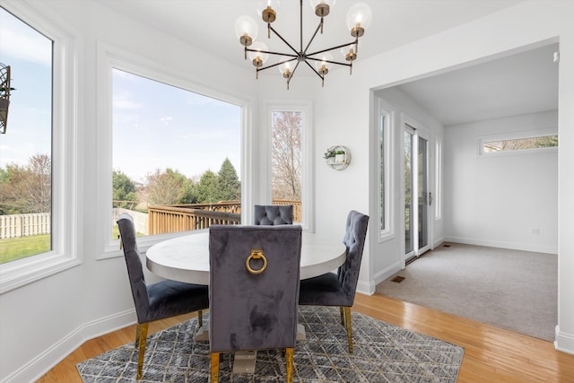 dining space with baseboards, a notable chandelier, and wood finished floors