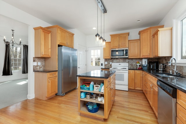 kitchen with appliances with stainless steel finishes, an inviting chandelier, a sink, a center island, and tasteful backsplash