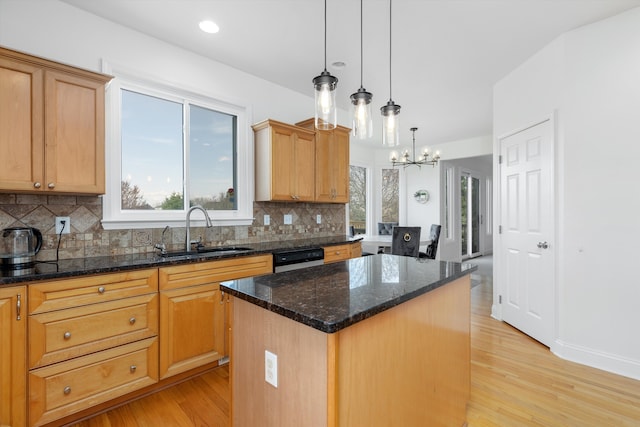 kitchen with a sink, decorative backsplash, light wood-style floors, and a kitchen island