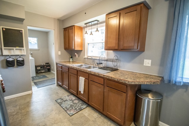 kitchen with a sink, hanging light fixtures, plenty of natural light, and brown cabinetry