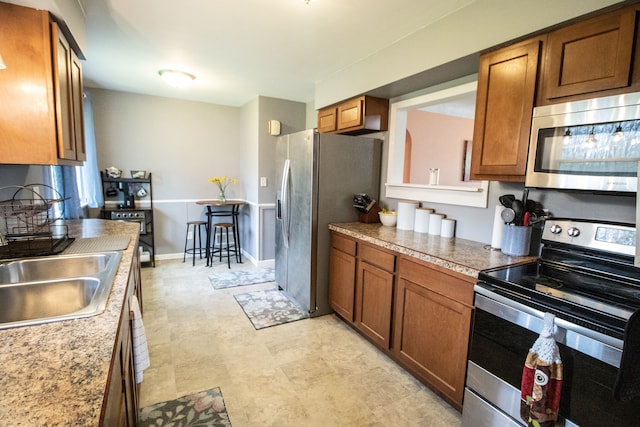 kitchen featuring appliances with stainless steel finishes, brown cabinetry, and a sink