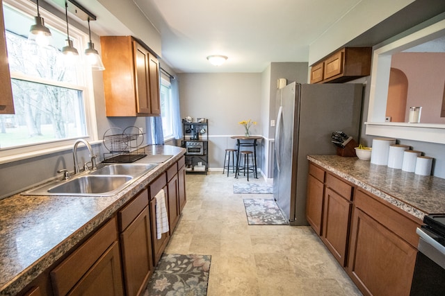 kitchen featuring a sink, dark countertops, brown cabinetry, and pendant lighting