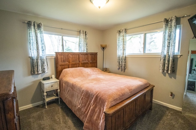 bedroom featuring dark carpet, baseboards, and multiple windows