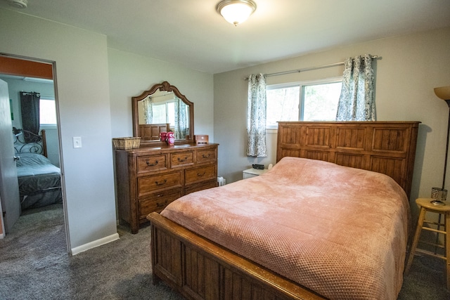 bedroom featuring baseboards, multiple windows, and dark carpet