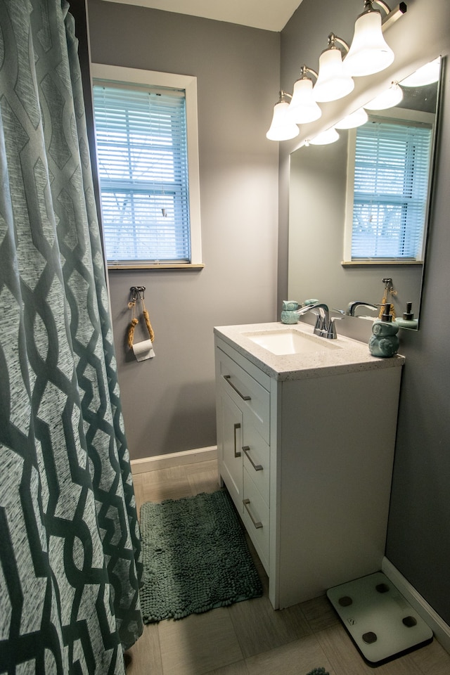 bathroom with vanity, baseboards, and a notable chandelier