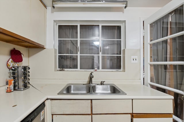 kitchen featuring light countertops, white cabinets, stainless steel dishwasher, and a sink