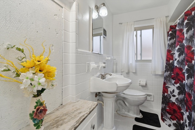full bath with curtained shower, toilet, and tile walls