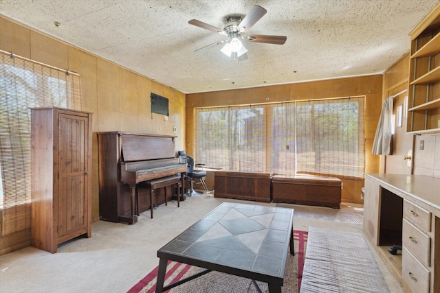 office area with light colored carpet, ceiling fan, and wood walls