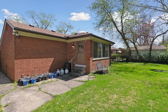 exterior space featuring a yard, brick siding, fence, and entry steps