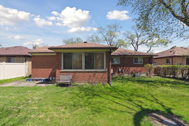 back of house with a lawn, brick siding, and fence