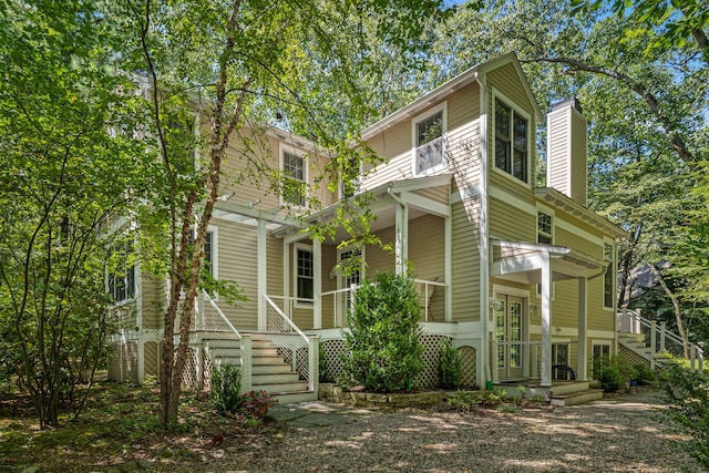 view of front of property with stairway, covered porch, and a chimney