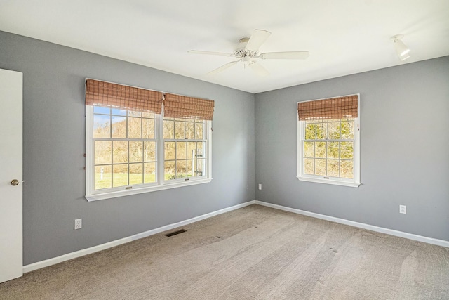 carpeted empty room with visible vents, baseboards, and ceiling fan
