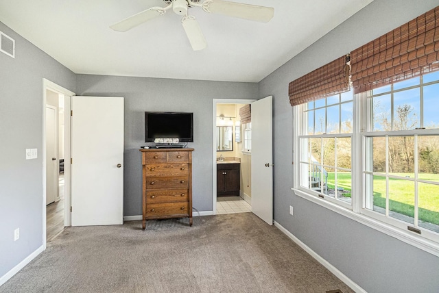 carpeted bedroom with a ceiling fan, visible vents, a sink, baseboards, and ensuite bath