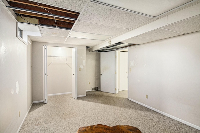 finished basement featuring baseboards, visible vents, a paneled ceiling, and carpet