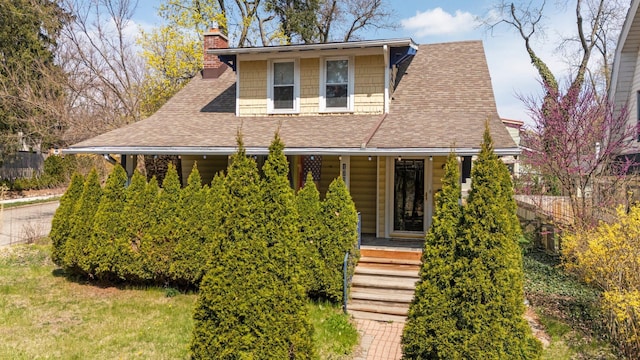 view of front of home with a porch, a chimney, and roof with shingles