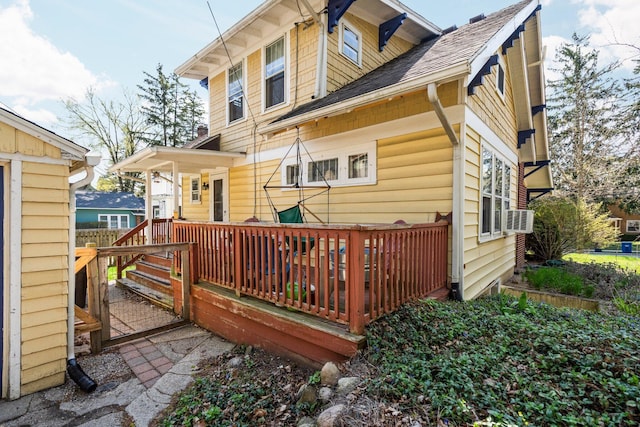 rear view of property featuring a deck, cooling unit, and roof with shingles