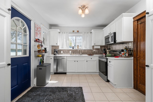 kitchen featuring white cabinets, a sink, light countertops, stainless steel appliances, and light tile patterned floors