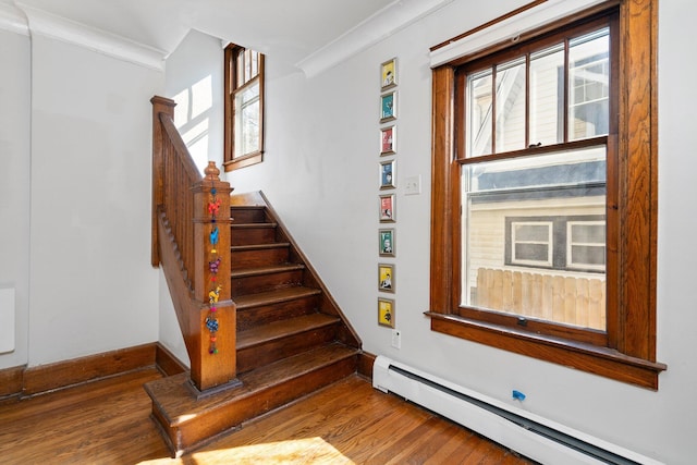 stairs featuring crown molding, baseboards, a baseboard heating unit, and wood finished floors