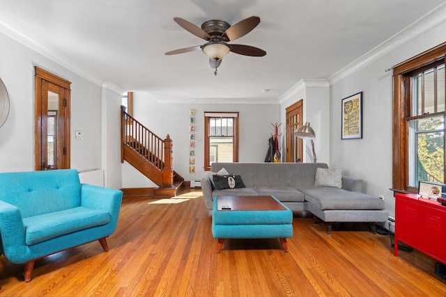 living area with light wood-style floors, ceiling fan, stairs, and a wealth of natural light