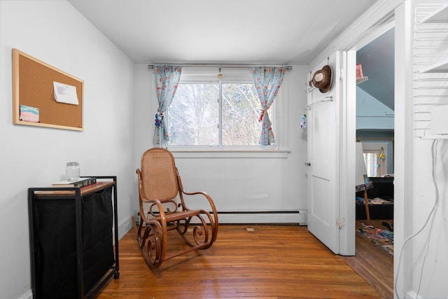 living area featuring baseboards, baseboard heating, and wood finished floors